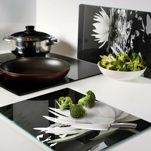 Schneidebrett aus Glas mit Seerosen auf schwarzem Hintergrund