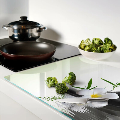 Schneidebrett mit Motiv aus Blumen und Kieselsteinen auf Wasser