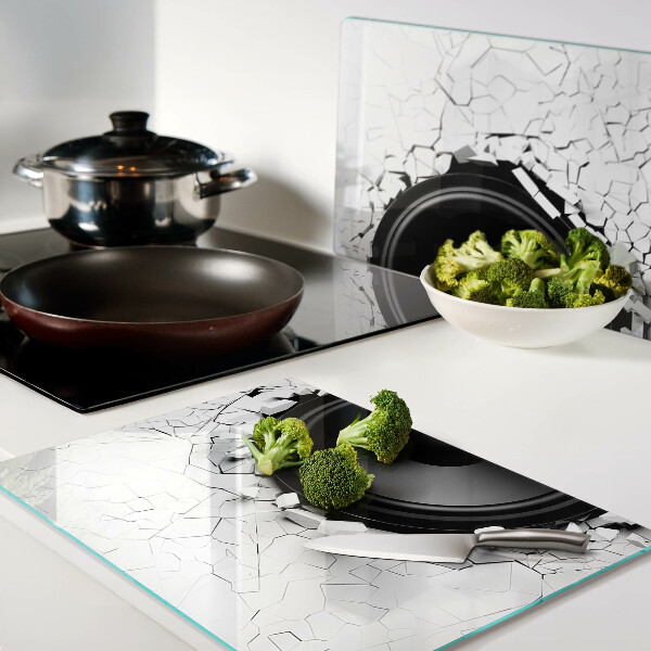 Schneidebrett mit Lautsprecher-Motiv vor einer zerbrochenen Wand