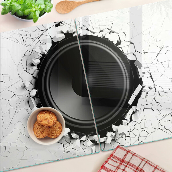 Schneidebrett mit Lautsprecher-Motiv vor einer zerbrochenen Wand