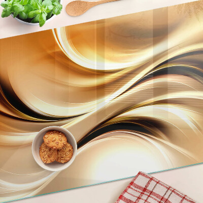 Glas-Schneidebrett mit abstraktem Wellenmotiv in Goldtönen