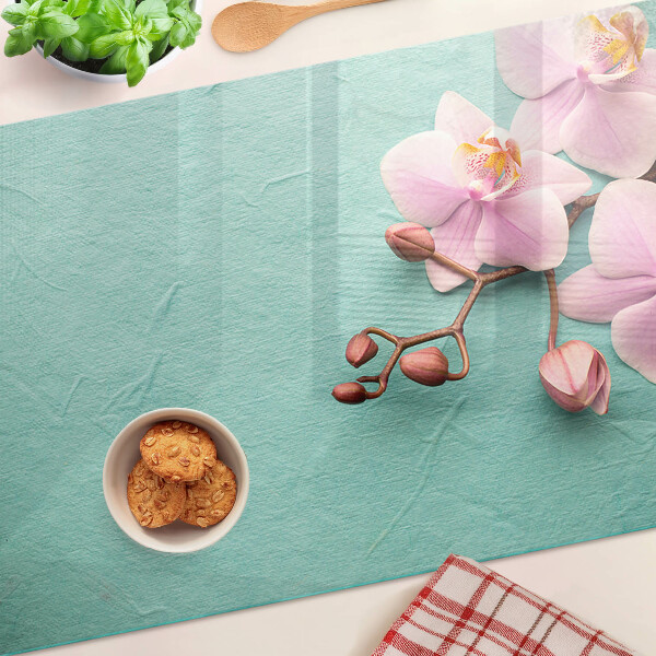 Glas Schneidebrett mit Orchideenmotiv auf blauem Hintergrund