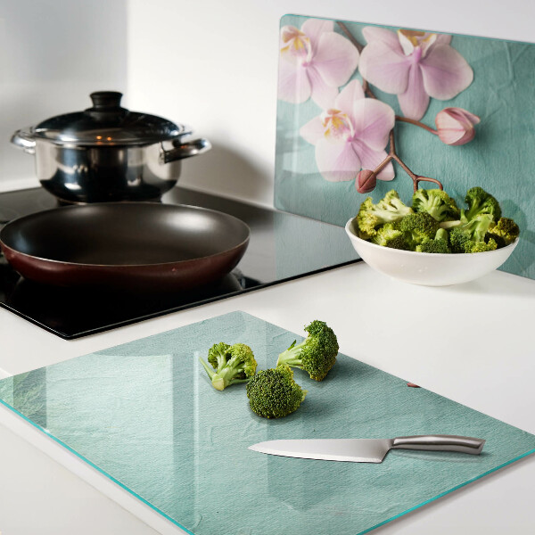 Glas Schneidebrett mit Orchideenmotiv auf blauem Hintergrund