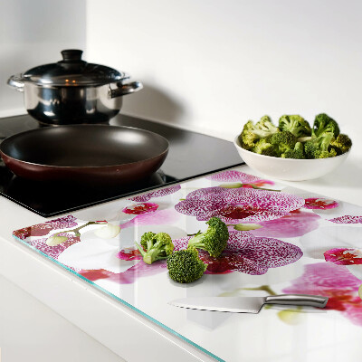 Glas-Schneidebrett mit Orchideen vor einem Fenster als Motiv