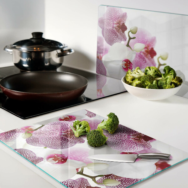 Glas-Schneidebrett mit Orchideen vor einem Fenster als Motiv