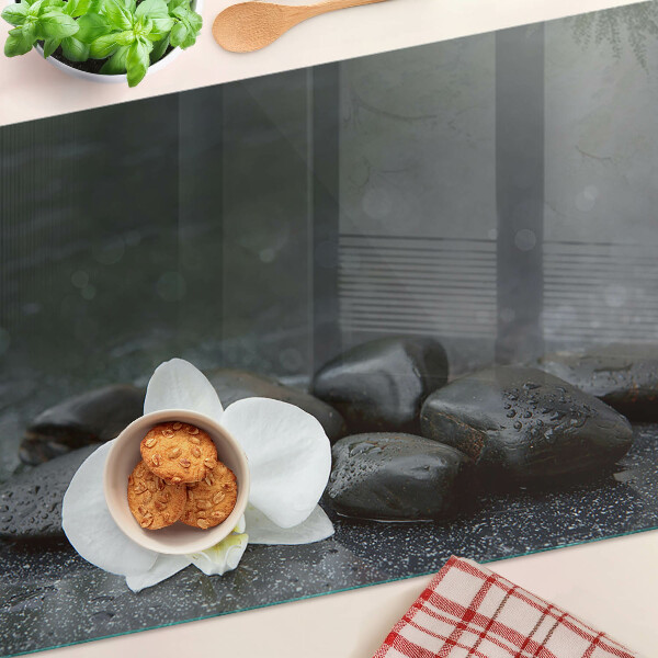 Schneidebrett mit Motiv einer Orchideenblüte auf Steinen