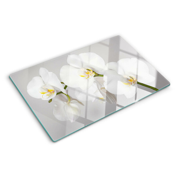 Schneidebrett mit Orchideen vor spiegelndem Hintergrund