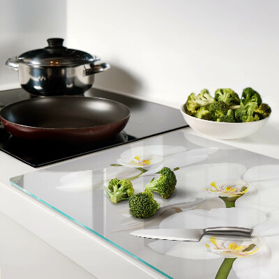 Schneidebrett mit Orchideen vor spiegelndem Hintergrund