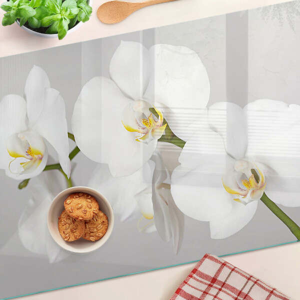 Schneidebrett mit Orchideen vor spiegelndem Hintergrund