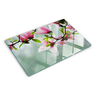 Schneidebrett mit Motiv aus Magnolienblüten vor grünem Hintergrund