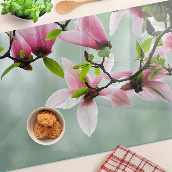 Schneidebrett mit Motiv aus Magnolienblüten vor grünem Hintergrund