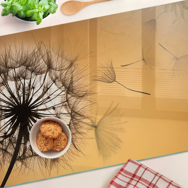 Schneidebrett Glas mit Löwenzahnmotiv vor dem Hintergrund eines Sonnenuntergangs