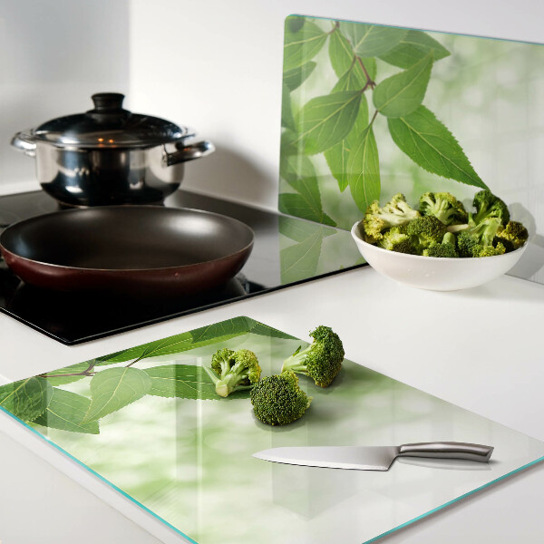 Glas-Schneidebrett mit Blattmotiv vor verschwommenem grünen Hintergrund