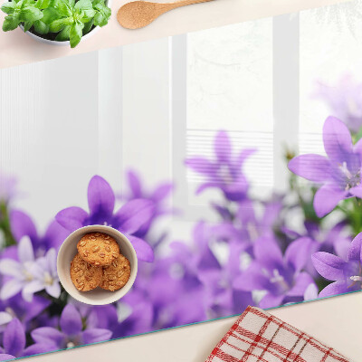 Glas-Schneidebrett mit lila Blumenmuster im Hintergrund