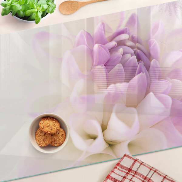 Glas-Schneidebrett mit einem Blumenarrangement in Lilatönen