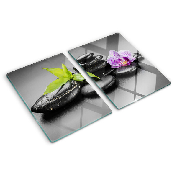 Schneidebrett Glas mit Steinen und Orchideen im Hintergrund