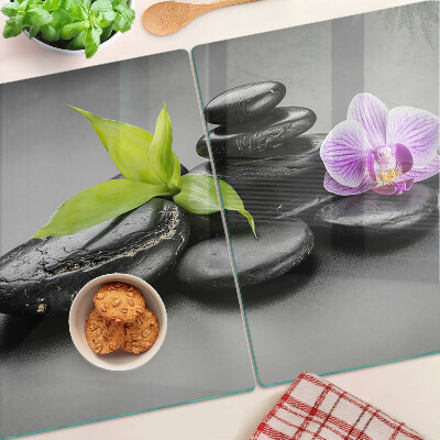 Schneidebrett Glas mit Steinen und Orchideen im Hintergrund