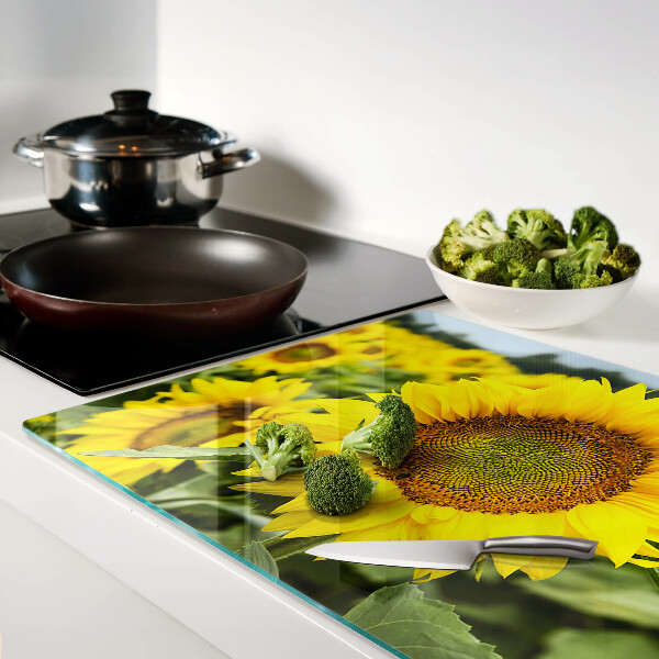 Schneidebrett aus Glas mit Sonnenblumen vor grünem Hintergrund