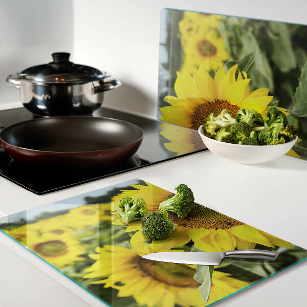 Schneidebrett aus Glas mit Sonnenblumen vor grünem Hintergrund