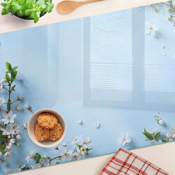 Glas-Schneidebrett mit Blumenmuster auf blauem Hintergrund