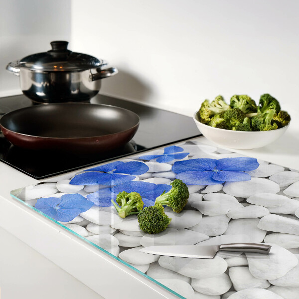 Glas-Schneidebrett mit blauem Blumenmotiv auf weißen Steinen