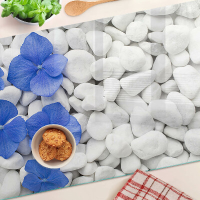 Glas-Schneidebrett mit blauem Blumenmotiv auf weißen Steinen