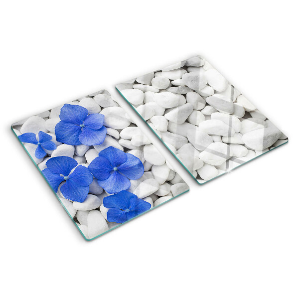 Glas-Schneidebrett mit blauem Blumenmotiv auf weißen Steinen
