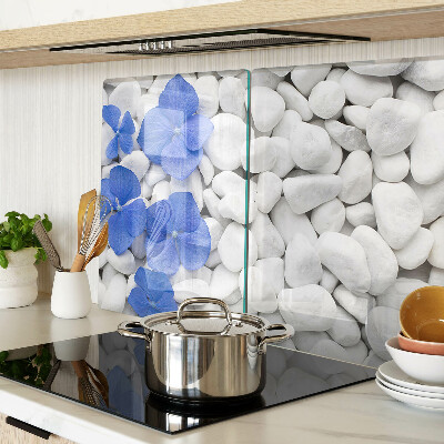 Glas-Schneidebrett mit blauem Blumenmotiv auf weißen Steinen