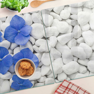 Glas-Schneidebrett mit blauem Blumenmotiv auf weißen Steinen