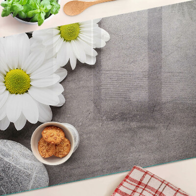 Schneidebrett Glas mit Blumen- und Steinemotiv im Hintergrund