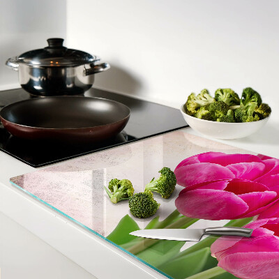 Schneidebrett Glas mit Tulpenblüten auf rosa Hintergrund