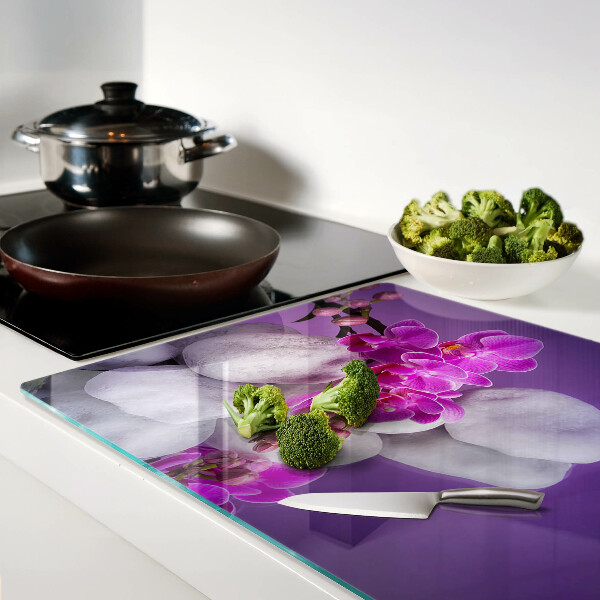 Schneidebrett mit Orchideenblüten vor einem steinernen Hintergrund