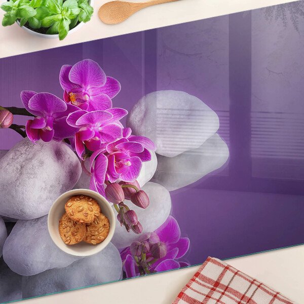 Schneidebrett mit Orchideenblüten vor einem steinernen Hintergrund