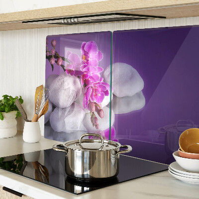 Schneidebrett mit Orchideenblüten vor einem steinernen Hintergrund