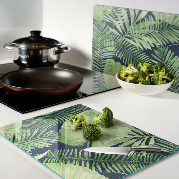 Glas schneidebrett mit tropischen Blättern auf dunklem Hintergrund