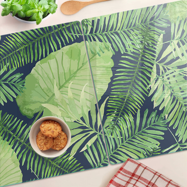 Glas schneidebrett mit tropischen Blättern auf dunklem Hintergrund