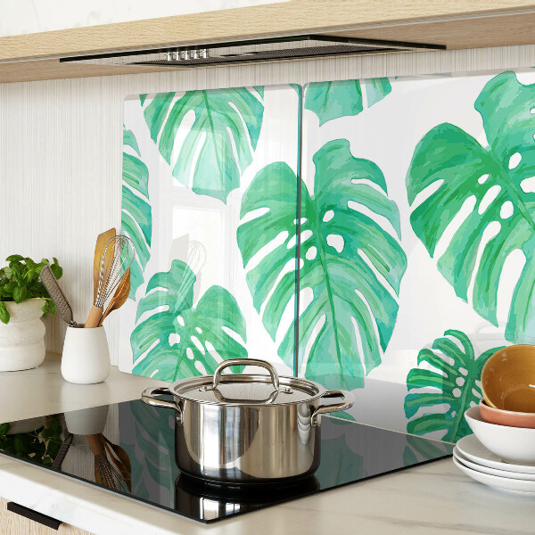 Glas-Schneidebrett mit Monstera-Blättern auf weißem Hintergrund