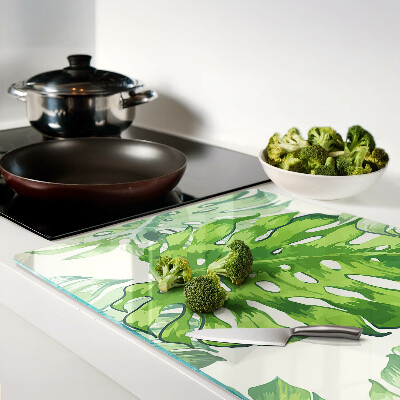 Schneidebrett mit Monstera-Blättern auf hellem Hintergrund