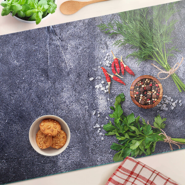 Schneidebrett Glas mit Motiv aus Kräutern und Gewürzen auf steinernem Hintergrund