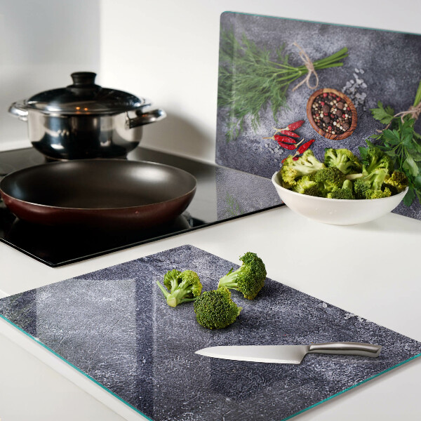 Schneidebrett Glas mit Motiv aus Kräutern und Gewürzen auf steinernem Hintergrund