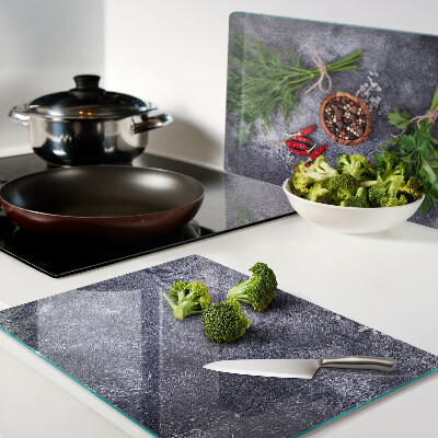 Schneidebrett Glas mit Motiv aus Kräutern und Gewürzen auf steinernem Hintergrund