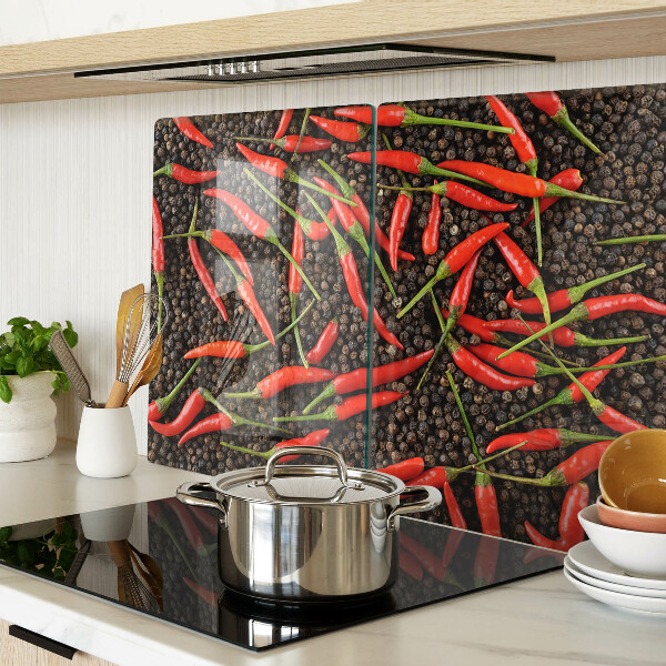 Schneidebrett mit Motiv aus Chilischoten auf schwarzem Pfeffer