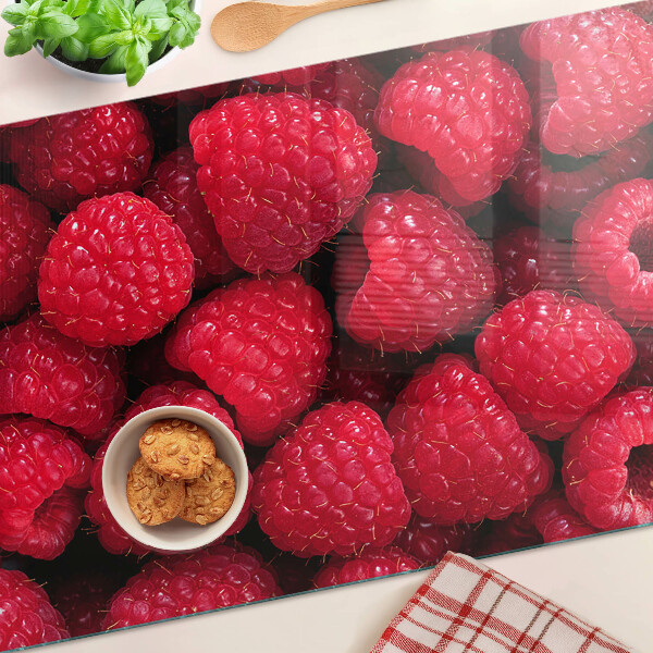 Schneidebrett Glas mit Himbeeren im Hintergrund