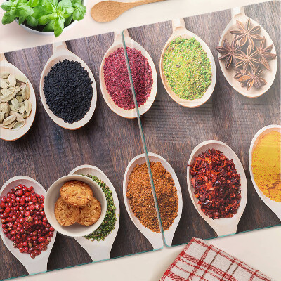 Schneidebrett Glas mit Gewürzen in Löffeln als Dekoration