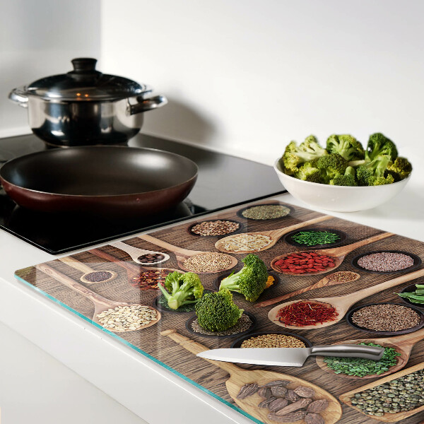 Glas-Schneidebrett mit Motiv aus Gewürzen und Kräutern in Holzlöffeln