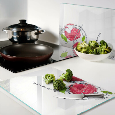 Glas schneidebrett Himbeeren in Wasser mit Blättern