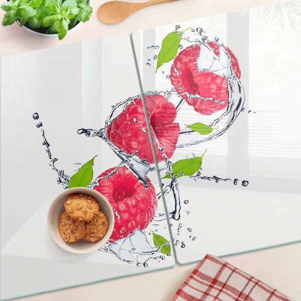 Glas schneidebrett Himbeeren in Wasser mit Blättern
