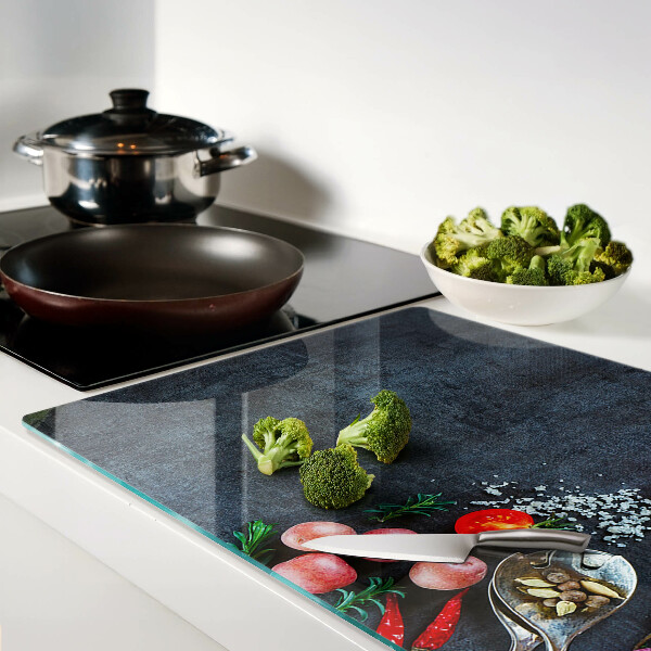 Glas-Schneidebrett mit Motiv von Gemüse und Gewürzen auf dunklem Hintergrund