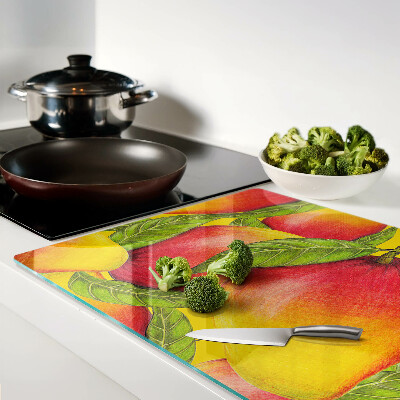 Glas-Schneidebrett mit Paprika vor grünem Blätterhintergrund