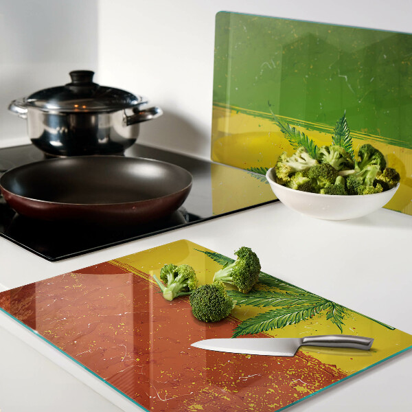 Glas-Schneidebrett mit Cannabisblatt auf farbigem Hintergrund